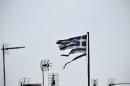 A frayed Greek national flag flutters among antennas atop a building in central Athens