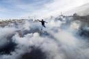 A Palestinian protester jumps as tear gas fired by Israeli soldiers rises during clashes in Jalazoun refugee camp near Ramallah
