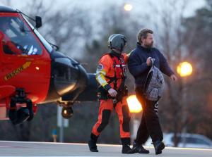 Louis Jordan, right, walks from the Coast Guard helicopter …