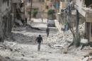 People walk on the rubble of damaged buildings after an airstrike in the rebel held area of Aleppo's Baedeen district
