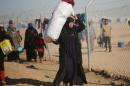 Displaced Iraqi woman, who fled the Islamic State stronghold of Mosul, carries her belongings at Khazer camp