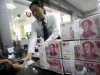 An employee hands Renminbi banknotes to a customer at a branch of the Industry and Commercial Bank of China in Hefei