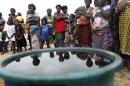 Villagers stand near a container containing crude oil collected by villagers as sample at the shore of the Atlantic ocean, days after Royal Dutch Shell's Bonga off-shore oil spill, in Nigeria's delta state
