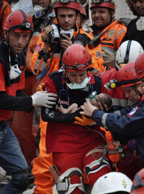 Rescue workers carry a baby from a collapsed building in Ercis