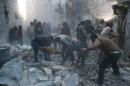 Rescue workers and pedestrians clear debris after an alleged air strike by Syrian government forces on a district of Aleppo on November 12, 2014