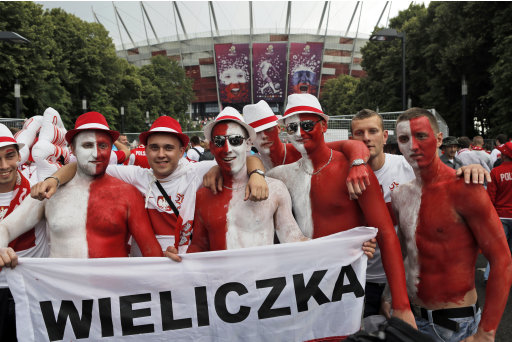 Polish soccer fans, wearing the colors of their home team, wait for the start of the opening match of the Euro 2012 soccer championship Group A match between Poland and Greece in Warsaw, Poland, Friday, June 8, 2012. (AP Photo/Gero Breloer)
