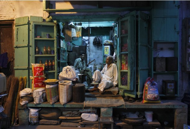A shopkeeper and his sales assistant wait for customers inside a family-owned grocery store in an alley in the old quarters of Delhi