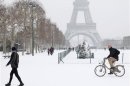 A man rides a Velib bicycle as he makes his way on a snow-covered area near the Eiffel Tower in Paris