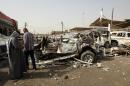 Iraqis stand near burnt out vehicles after a car bombing in Baghdad on March 7, 2014