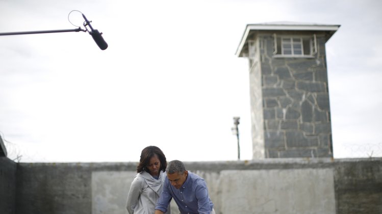 U.S. President Obama writes in a guest book as he tours Robben Island with the First lady near Cape Town