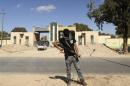 A militia stands guard in front of the entrance to the February 17 militia camp after Libyan irregular forces clashed with them in Benghazi
