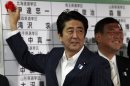 Japan's PMAbe, and the leader of the ruling LDP, smiles as he puts a rosette on a name of a candidate, who is expected to win, at the party headquarters in Tokyo