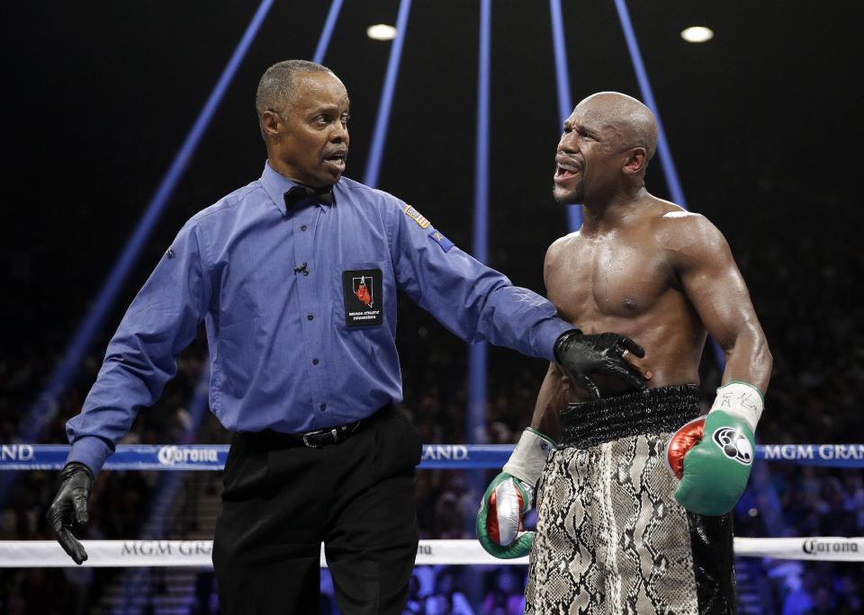 FILE - In this Sept. 13, 2014, file photo, Floyd Mayweather speaks to referee Kenny Bayless, left, after he claimed that Marcos Maidana bit his hand...