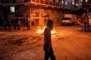 A far left-wing protester walks past a burning barricade during clashes with riot police in Istanbul's Gazi neighborhood