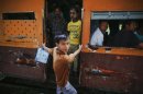 A young man hangs from a moving train in Yangon's suburbs
