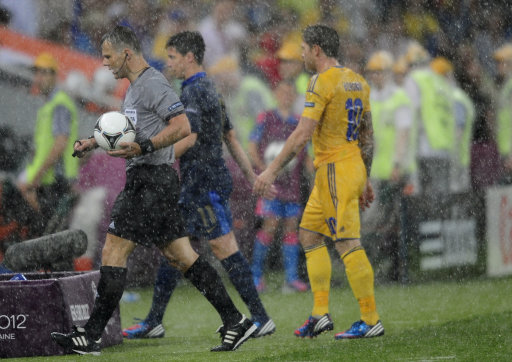 Dutch referee Bjoern Kuipers, left, and players leave the pitch after the Euro 2012 soccer championship Group D match between Ukraine and France was suspended due to heavy rain in Donetsk, Ukraine, Friday, June 15, 2012. (AP Photo/Manu Fernandez)