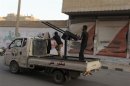 A Free Syrian Army fighter aims an anti-aircraft gun as he stands on the back of a truck in Deir al-Zor