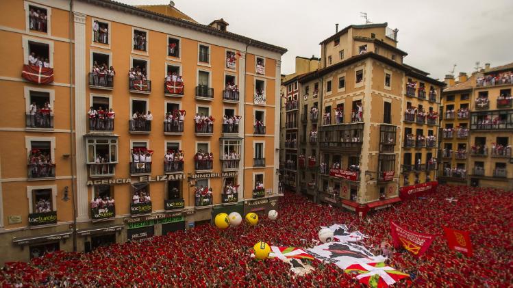 Revelers hold up traditional red neckties during the launch of the "Chupinazo" rocket, to celebrate the official opening of the 2014 San Fermin fiestas in Pamplona, Spain, Sunday, July 6, 2014. Revelers from around the world turned out here to kick off the festival with a messy party in the Pamplona town square, one day before the first of eight days of the running of the bulls glorified by Ernest Hemingway's 1926 novel "The Sun Also Rises." (AP Photo/Andres Kudacki)