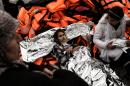 A girl wrapped in a survival blanket lies on life jackets as migrants and refugees arrive on the Greek island of Lesbos while crossing the Aegean Sea from Turkey on March 2, 2016