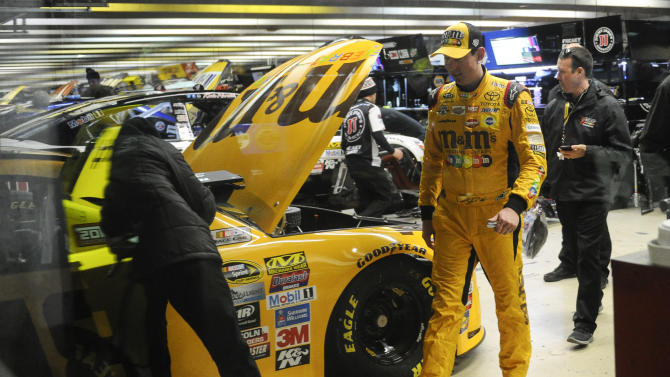 Kyle Busch, right, walks past his car in the the garage after it failed post-qualifying inspection for Sunday&#39;s NASCAR Sprint Cup auto race at Atlanta Motor Speedway, Friday, Feb. 26, 2016, in Hampton, Ga. (AP Photo/John Amis)