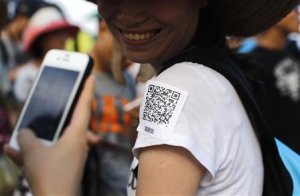 A man uses his phone to scan a QR code sticker, which …
