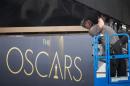 A man arranges a digital display above the red carpet during preparations for the 86th Academy Awards in Hollywood, California