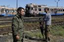 Pro-Russian separatists stand in front of destroyed trains at a railway station in the eastern Ukrainian town of Ilovaysk