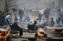 Refugees warm themselves near bonfires in a refugee camp located in former military barracks in the town of Harmanli, south-east of the Bulgarian capital Sofia, on November 12, 2013