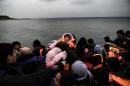People hold a baby as migrants and refugees arrive on the Greek island of Lesbos while crossing the Aegean Sea from Turkey