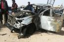 People stand at the scene of a car bomb explosion in the eastern city of Tobruk