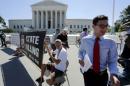 A news assistant runs to his co-workers with copies of court decisions past anti-death penalty demonstrators in front of the U.S. Supreme Court building in Washington