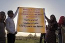 Egyptian villagers hold a banner in front of the 4,500-year-old "bent" pyramid, of Pharaoh Sneferu known for its oddly shaped profile, outside the village of Dahshour, 50 miles (80 Kilometers) south of Cairo, Egypt, Monday, April 29, 2013. Protesters held a rally on Monday against the continued construction of a modern cemetery at the foot of Egypt's first pyramids and its oldest temples. Authorities have so far failed to stop the construction, despite earlier promises to do so. Looting has also spread in the site that has witnessed little excavation, in the absence of security or law enforcement. Arabic on the banner is translated into English at top. (AP Photo/Amr Nabil)