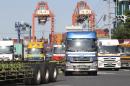 In this Friday, Sept. 26, 2014 photo, trucks leave a container wharf in Tokyo. Japan reported Monday, Nov. 17 that its economy contracted at a real annual rate of 1.6 percent in July-September in the second straight quarterly decline. Most economists had forecast the world's third-biggest economy expanded at about a 2 percent pace. The negative growth figure was much lower than expected and makes it very likely Prime Minister Shinzo Abe will delay implementation of a sales tax hike planned for October, 2015. (AP Photo/Koji Sasahara)