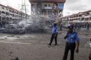 Policemen walk towards burnt vehicles at the scene of a blast at a business district in Abuja