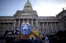 A man wearing a mask on his head takes a picture of the Congress as he protests the comprehensive judicial reform proposed by President Cristina Fernandez in Buenos Aires, Argentina, Wednesday, April 24, 2013. Lawmakers have started Wednesday to address three bills of the controversial judicial system, two of them regarding the regulation of injunctions against the state and the creation of three new Cassation Courts. (AP Photo/Natacha Pisarenko)