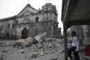 A private guard stands near the damaged Basilica of the Holy Child following a 7.2-magnitude earthquake that hit Cebu city in central Philippines and toppled the bell tower of the Philippines' oldest church Tuesday, Oct. 15, 2013. The tremor collapsed buildings, cracked roads and toppled the bell tower of the church Tuesday morning, causing multiple deaths across the central region and sending terrified residents into deadly stampedes. (AP Photo/Bullit Marquez)