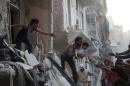 A man evacuates a child from a building following a reported barrel bomb attack by Syrian government forces on Aleppo, on May 30, 2015