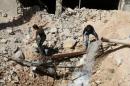Men inspect a hole in the ground filled with water in a damaged site after airstrikes on the rebel held Tariq al-Bab neighbourhood of Aleppo