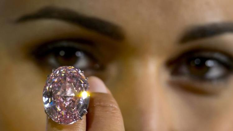 A model presents a 59.6-carat pink diamond on September 25, 2013 that was auctioned in Geneva Wednesday for $83 million, a world record for a gemstone