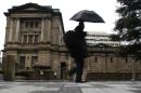 A pedestrian holding an umbrella to take shelter from rain and hail walks past the Bank of Japan headquarters building in Tokyo