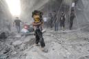 A Syrian man carries two girls covered with dust following a reported air strike by government forces on July 9, 2014 in the northern city of Aleppo