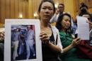 The wife of a passenger aboard the missing Malaysia Airlines Flight MH370, holds a picture of her husband walking with Malaysia's Prime Minister Razak, at a news conference in Putrajaya
