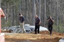A man, left, walks with investigators Monday, April 8, 2013, around the scene of a collapsed construction site where two children died when the dirt walls collapsed Sunday on Cedarbrook Court in Stanley, N.C. (AP Photo/Bob Leverone)
