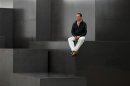 British artist Gormley poses for a photograph on his sculpture 'Model' at a White Cube gallery in London