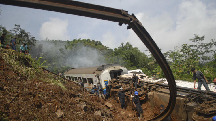 Worker prepare to remove derailed trains in Tasikmalaya, West Java, Indonesia, Saturday, April 5, 2014. A passenger train hit mounds of mud triggered by a landslide and derailed in central Indonesia, killing at least three people and injuring seven, a railway official said Saturday. (AP Photo/Erwin Gobel)