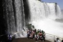 Tourists pose for photos with Iguazu Falls in the background from an observation platform at the Iguazu National Park