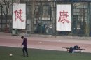 In this Saturday, Jan. 19, 2013 photo. a college student kicks a soccer ball in front of Chinese characters on the fence reading "good health" in Beijing. Despite its formidable performance in recent Olympic Games, China has found itself in a crisis of declining fitness among its youngsters. (AP Photo/Alexander F. Yuan)