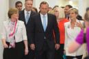 Australian Prime Minister Tony Abbott, center, surrounded by supporters, walks to a meeting to face a potential leadership challenge Monday, Feb. 9, 2015. Beleaguered Prime Minister Abbott survived an internal government challenge to his leadership on Monday, despite a revolt by dozens of colleagues that leaves him politically damaged.(AP Photo/Andrew Taylor)