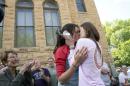 Jennifer Rambo, right, of Fort Smith, Ark., kisses her partner Kristin Seaton, left, of Jacksonville, Ark., following their marriage ceremony in front of the Carroll County Courthouse as Sheryl Maples, far left, the lead attorney who filed the Wright v. the State of Arkansas lawsuit, looks on Saturday, May 10, 2014, in Eureka Springs, Ark. Rambo and Seaton were the first same-sex couple to be granted a marriage license in Eureka Springs after a judge overturned Amendment 83, which banned same-sex marriage in the state of Arkansas. (AP Photo/Sarah Bentham)