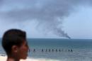 Palestinian watches as smokes rises from an Egyptian coastguard vessel on the coast of northern Sinai, as seen from the border of southern Gaza Strip with Egypt